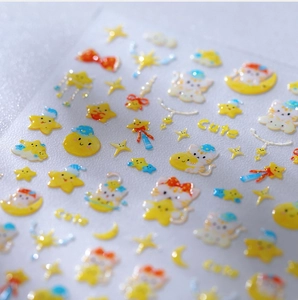 Macro shot of 3D crystal nail stickers featuring cute cats, stars, and moon details