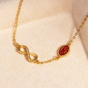 Detail eines 14k Goldarmbands mit Unendlichkeitssymbol und rotem Rugbyball-Anhänger