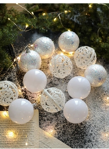 Detail of white Christmas balls with glitter and patterns on a snowy festive background