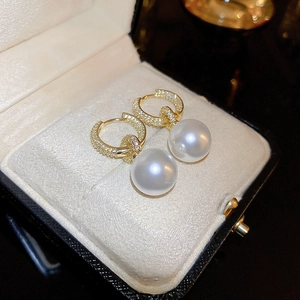 Vue macro de boucles d'oreilles dorées avec zircons et perles blanches de luxe