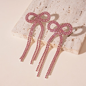 Vue détaillée des boucles d'oreilles nœud en cristal rose à longs pompons fins