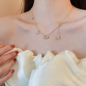Detail of 18k gold plated necklace featuring floral and handbag shaped pendants on model