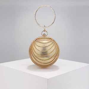 Detail of golden spherical evening bag with rhinestones and round metal handle