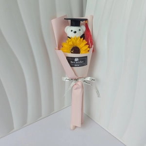 Detail of graduation bear plush and sunflower bouquet wrapped in pink gift paper