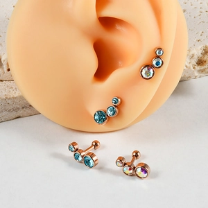 Détail de clous d'oreille en acier rose gold avec cristaux bleus et AB sur modèle d'oreille