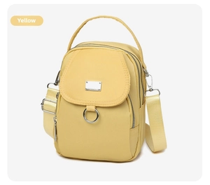 Close-up of yellow nylon crossbody bag with multi-layer zippers and top handle details