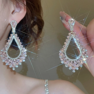 Détail de boucles d'oreilles pendantes avec cristaux roses et bordures en zircone