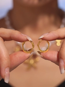 Gros plan de boucles d'oreilles créoles Mobius plaquées or avec une texture torsadée