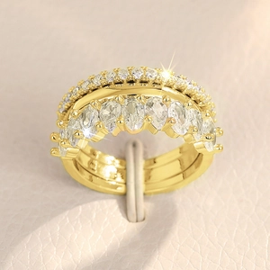 Dettaglio macro di un set di tre anelli impilabili in oro con zirconi a taglio marquise