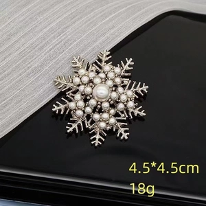 Detaillierte Schneeflocken-Brosche mit Perlen und Metalltextur auf schwarzem Grund
