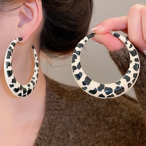 Close-up of large hoop earrings with black and white cow print for autumn fashion outfits