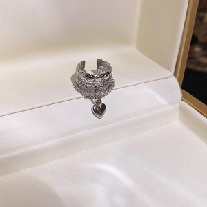 Close-up of silver multilayer ear cuff with heart pendant and quilted texture detail
