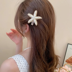 Vue détaillée d'une pince à cheveux étoile de mer en raphia tressé avec perle