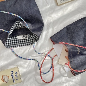 Detail of vintage denim tote bag showing colorful beaded straps and checkered lining