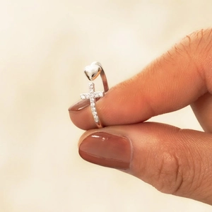Bague ajustable argentée avec cœur en zircon et croix sur fond beige minimaliste