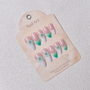 Detailed view of 3D floral press-on nails with white petals and green accents on display card