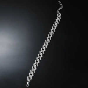 Detail of silver-tone iced out Cuban link anklet with diamond accents and lobster clasp