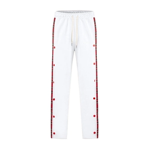 Detail of white sweatpants featuring red and green plaid side stripes and metal snap buttons