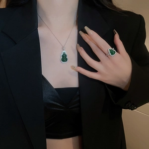 Macro shot of green resin gourd necklace and ring set with zircons on a model