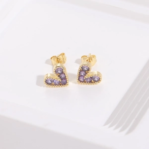 Elegant gold heart earrings set with purple gemstones on a clean white textured surface