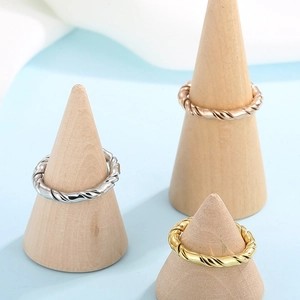 Minimalist twisted metal rings in silver, rose gold, and gold on wooden stands