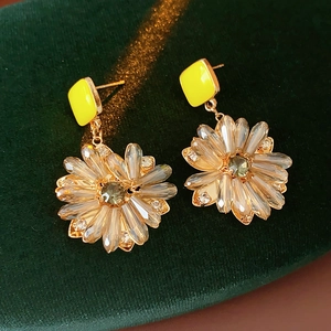 Detailaufnahme der Goldblumen-Ohrringe mit Kristallen auf grünem Samthintergrund