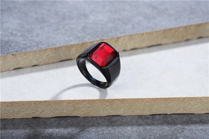 Detailopname van een herenring in punkstijl van zwart titanium met grote rode rechthoekige steen