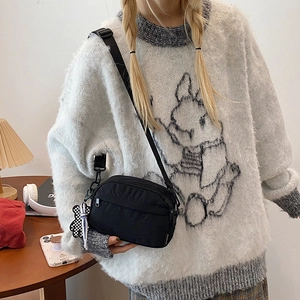 Modern black nylon crossbody bag with cute checkered bear charm for casual style