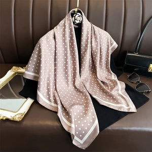 Eleganter rosa Seidenschal mit Punkten auf Ledersofa mit luxuriösem Zubehör