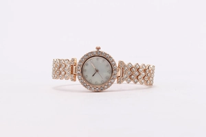 Detail of rose gold women's watch featuring a mother of pearl dial and crystal accents