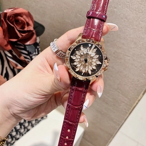 Close-up of DIMINI watch with rotating rhinestone flower dial and burgundy leather strap
