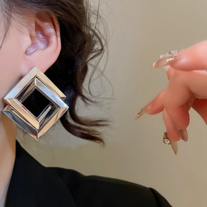 Close-up of geometric overlapping silver diamond earrings worn by a fashion model
