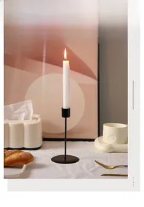 Detail of Nordic minimalist black metal candlestick holder with a tall white candle