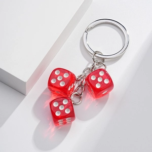 Close-up of three red transparent dice pendants with white dots on a metal keychain