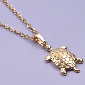 Detailed close-up of a 18k gold plated turtle pendant on a matching O-chain necklace