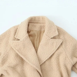 Close-up of beige Sherpa coat showing stylish lapel collar and soft textured wool fabric