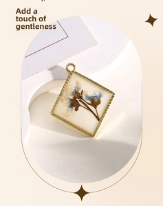 Close-up of diamond-shaped resin pendant with dried flowers and gold textured metal edge