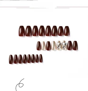 Gros plan d'ongles ballerine bordeaux et paillettes dorées avec décors de strass