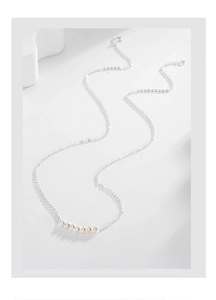 Detail of S925 silver necklace with seven aligned white pearls on a minimalist white background