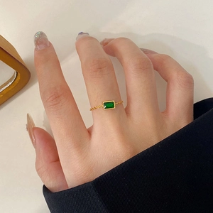 Macro detail of adjustable gold chain ring featuring a rectangular green zircon stone
