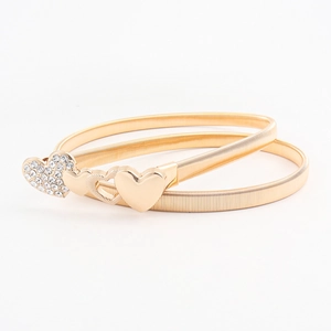 Detailed view of a gold elastic belt featuring a rhinestone heart-shaped interlocking buckle