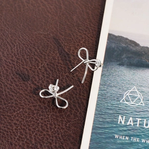 Élégantes boucles d'oreilles nœuds en argent poli sur une surface en cuir foncé