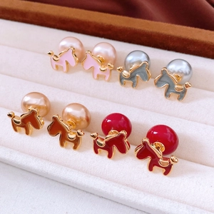 Detailed view of horse-shaped pearl earrings in pink, grey, amber, and red finishes