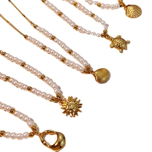 Elegant gold pearl necklaces with shell and sea turtle charms on white backdrop