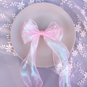 Close-up of pink iridescent tulle bow hairclip on a decorative plate with soft lighting