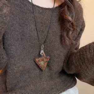 Plush triangle pendant necklace with metal tassel on a brown vintage knit sweater
