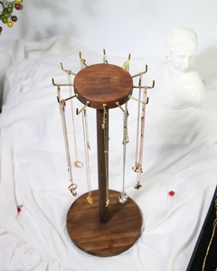 Detail of wooden necklace display stand with gold hooks and walnut finish on white silk
