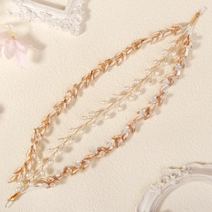Detail of bridal hair vine with pearls, metal leaves and white flowers on beige texture
