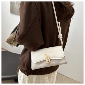 Detail of cream white leather shoulder bag featuring a gold buckle and knotted strap design