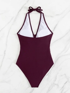 Detail of burgundy halter one-piece swimsuit with V-neckline on marble background